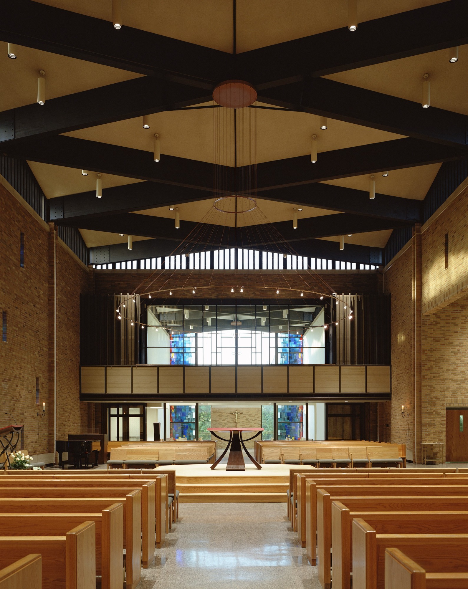 Pews facing the altar beneath exposed roof beams in St. Thomas Aquinas Catholic Church.