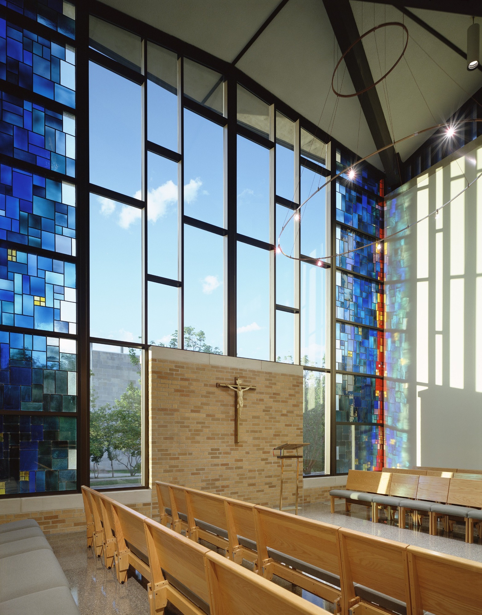 Blue stained-glass panels beside tall sanctuary windows at St. Thomas Aquinas Catholic Church.