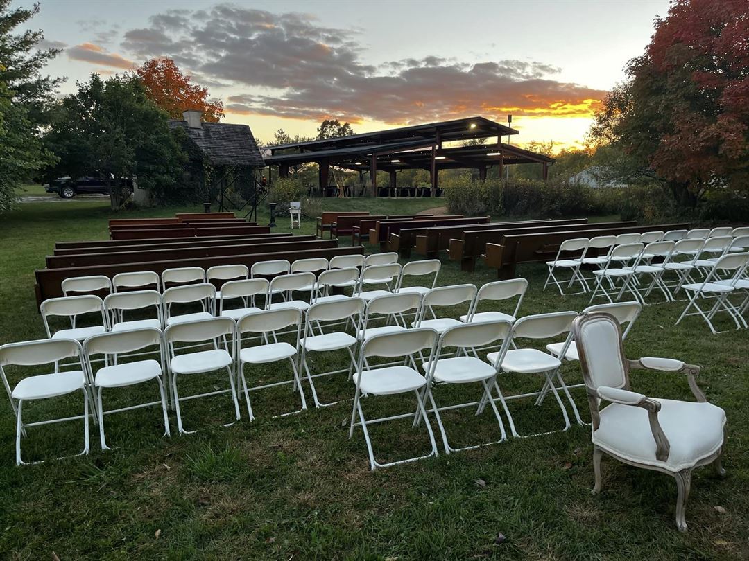 Lawn and pavilion at Raspberry Hill, set with chairs at sunset.