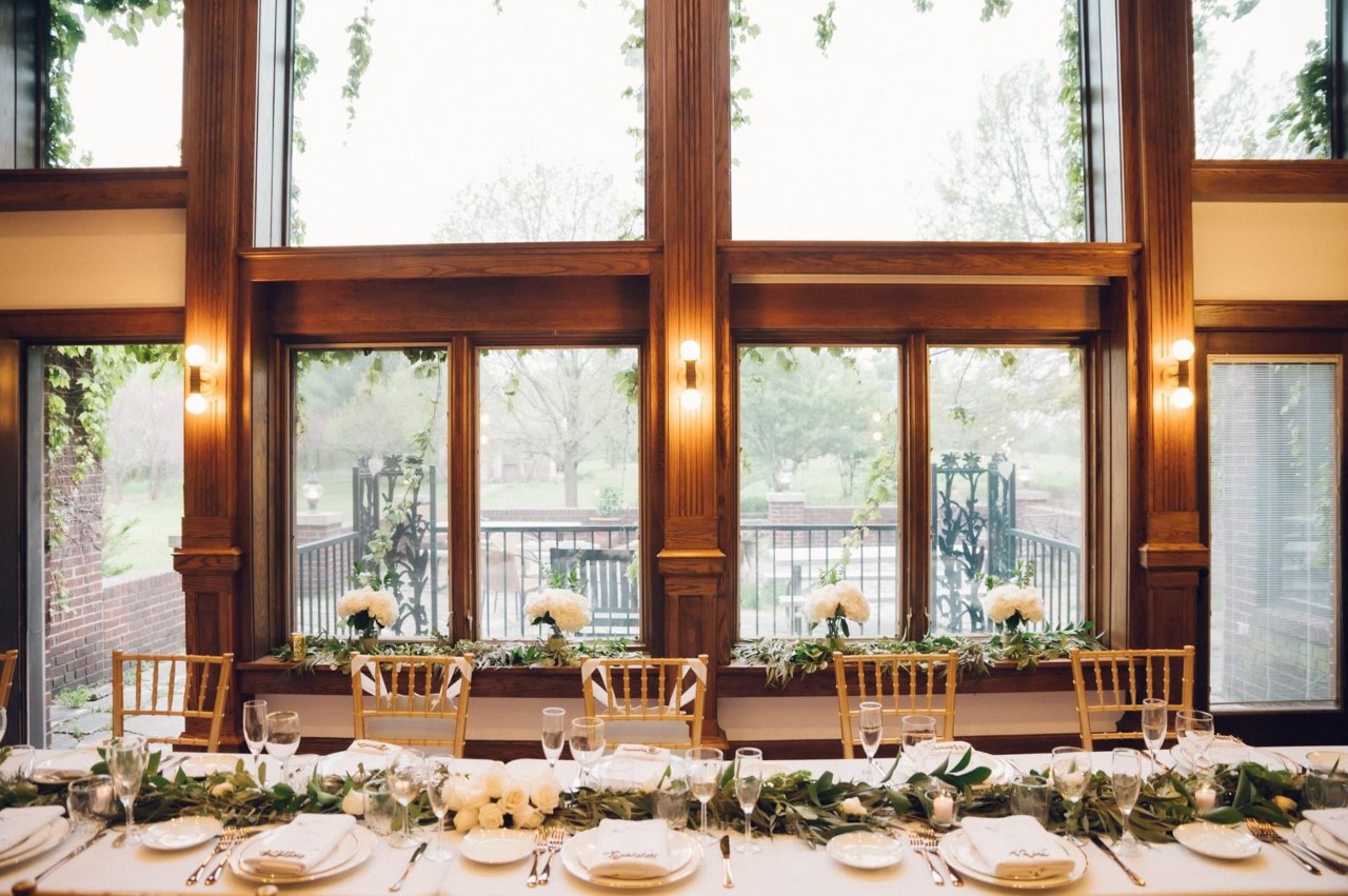 A decorated reception table beneath tall wooden windows at Raspberry Hill.